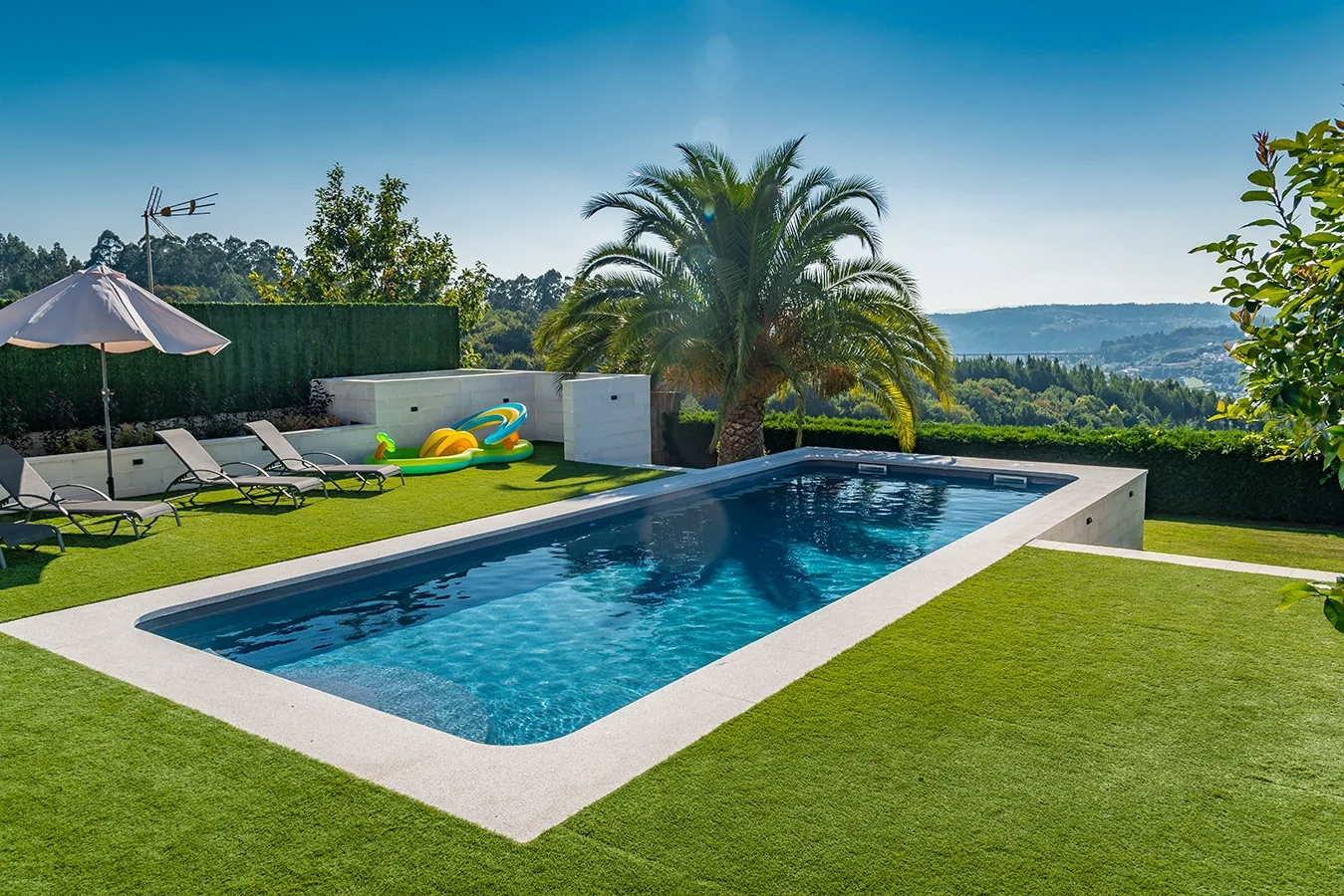 Piscina prefabricada entre jardines y una palmera